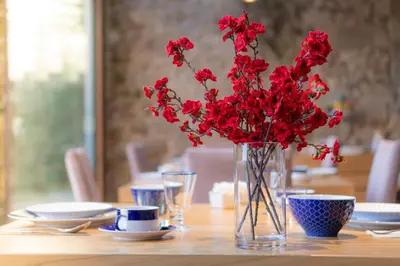 a vase filled with red flowers sitting on a table at ACOUGA Hotel Boutique in Celanova
