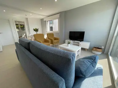 a living room with a blue couch and a television at Adosado A ( 5 hab) in Foz