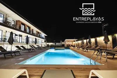 a swimming pool at night with chairs and umbrellas at Adosado A ( 5 hab) in Foz