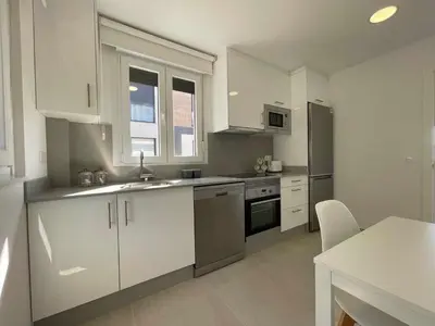 a kitchen with white cabinets and a sink and a table at Adosado A ( 5 hab) in Foz