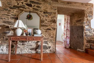 a room with a stone wall with a table and a mirror at Casa das Regueiras in Santiago de Compostela