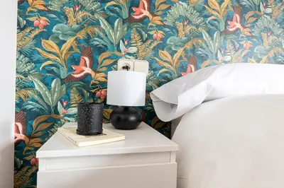 a bedroom with a bedside table with a lamp and a tropical wallpaper at Casa das Regueiras in Santiago de Compostela