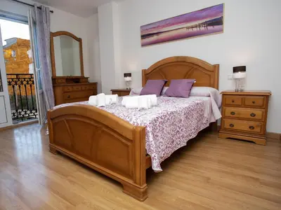 a bedroom with a large wooden bed with purple pillows at VIVAVI piso in Sarria