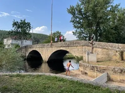 a man walking on a bridge over a river at Pallozas Turisticas Ridicodias - A Pedra in Matamá