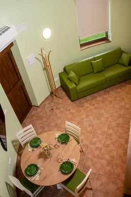 a table with chairs and a green couch in a living room at Pallozas Turisticas Ridicodias - A Pedra in Matamá