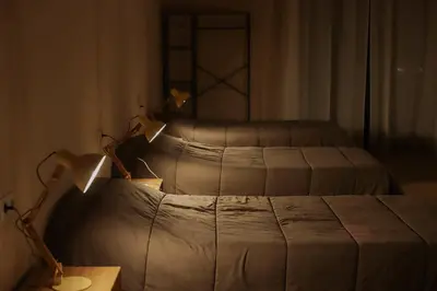 two beds in a bedroom with a table and lamps at Viña Femita in Villafranca del Bierzo