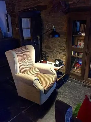 a living room with a couch and a stone wall at Casa rural **** El Barreiro. Ideal para familias. in Sorbeda