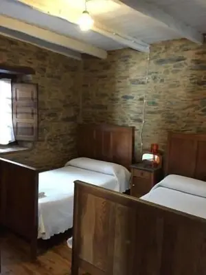 a bedroom with two beds and a brick wall at Casa rural **** El Barreiro. Ideal para familias. in Sorbeda