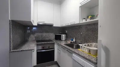 a kitchen with white cabinets and a sink and a microwave at Precioso apartamento en ares in Ares
