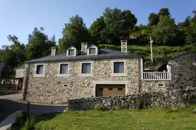 a stone house with a stone wall at Vivienda Uso Turístico As Quintas in Suarbol