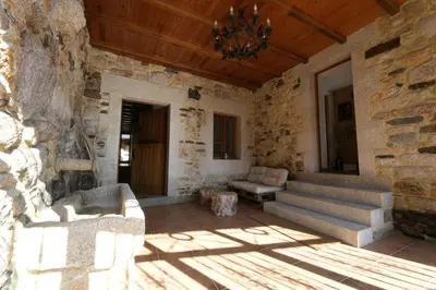 a porch of a stone building with a chandelier at Vivienda Uso Turístico As Quintas in Suarbol