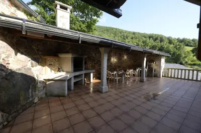a stone building with a patio with a table and chairs at Vivienda Uso Turístico As Quintas in Suarbol