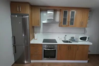 a kitchen with wooden cabinets and a stainless steel refrigerator at Vivienda Uso Turístico As Quintas in Suarbol