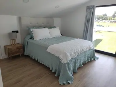 a bedroom with a bed with a green blanket and a window at POLAS BEACH LOFT in Nois