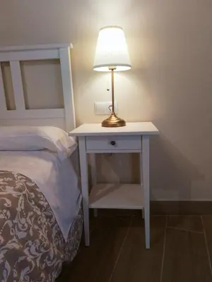 a table with a lamp on it next to a bed at Hostel & Rooms Casa Maia in Padrón