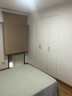 a bedroom with a bed and white cabinets and a window at Apartamento Centrico y Tranquilo El Rinconcito in Ourense