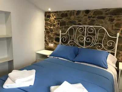a blue bed in a room with a stone wall at Casa Cea in Melide