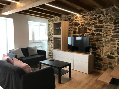 a living room with a tv and a stone wall at Casa Cea in Melide