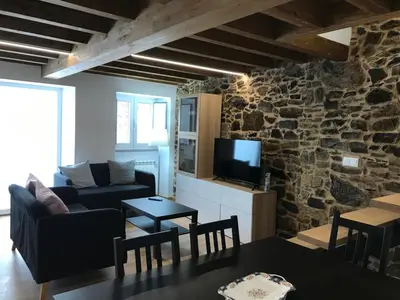 a living room with a stone wall with a couch and a table at Casa Cea in Melide