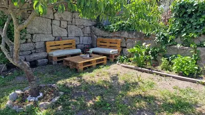 two benches and a table in front of a stone wall at Casa da Penela in Nogueira de Ramuin