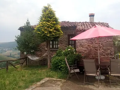 a house with a table and chairs and an umbrella at CASA CHANOS in Cangas del Narcea