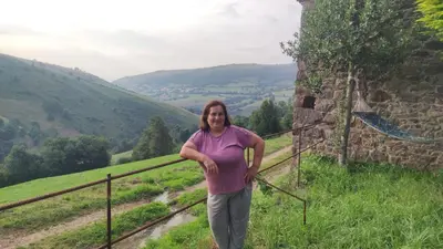 a woman is standing next to a fence at CASA CHANOS in Cangas del Narcea