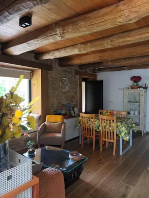 a living room with wooden ceilings and a table and chairs at Casa Os Prados da Albela in Tríacastela