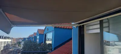 a balcony with awning on a blue and white building at ÁTICO 2 terrazas LEMASALUD in Ares