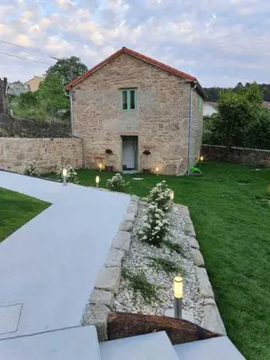 a stone house with a stone pathway in front of a yard at A Casa Do Boi in Amés