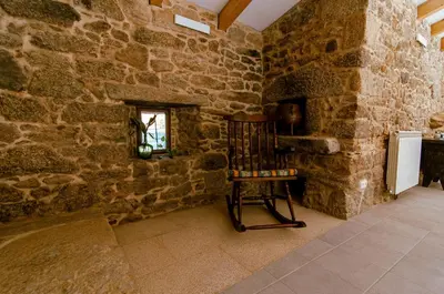 a room with a chair in a stone wall at A Casa Do Boi in Amés