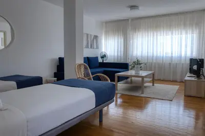 a bedroom with two beds and a desk and a window at Hospedería San Froilan in Lugo