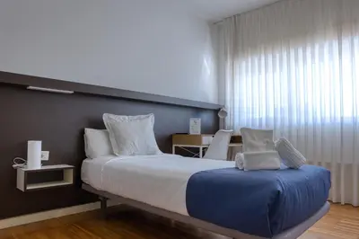 a bedroom with a bed and a chair and a window at Hospedería San Froilan in Lugo