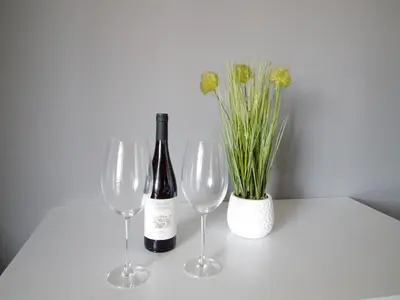 two wine glasses and a bottle and a vase with flowers at CASA MIRADOR REZA Alojamiento Termas in Ourense