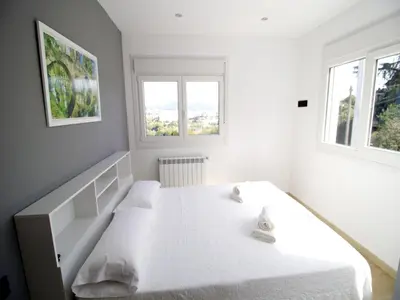 a bedroom with a white bed with two windows at CASA MIRADOR REZA Alojamiento Termas in Ourense