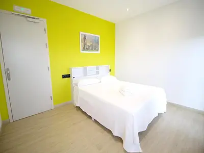 a white bed in a room with a yellow wall at CASA MIRADOR REZA Alojamiento Termas in Ourense