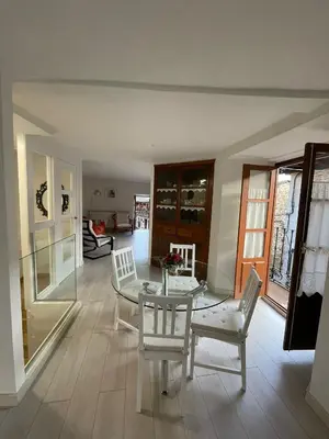 a dining room with a glass table and white chairs at Casa Tía Milagros in Puebla de Sanabria