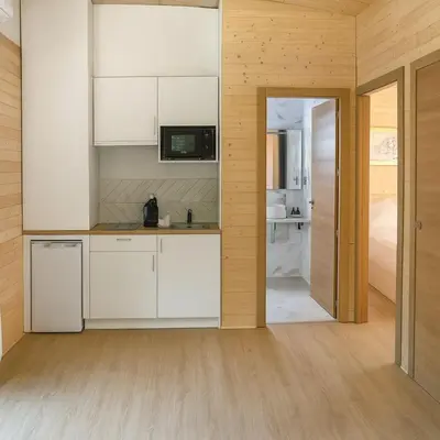 a kitchen with white cabinets and a refrigerator at Cabañas Compostela - Cabaña a Carballeira in Santiago de Compostela