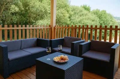 a patio with two couches and a table and glasses of wine at Cabañas Compostela - Cabaña a Carballeira in Santiago de Compostela