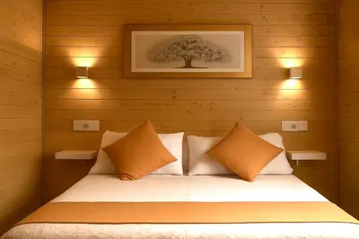 a bed in a wooden room with two lights at Cabañas Compostela - Cabaña a Carballeira in Santiago de Compostela