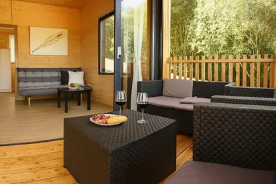 a patio with a couch and a table with a glass of wine at Cabañas Compostela - Cabaña a Carballeira in Santiago de Compostela