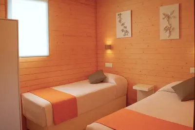a room with two beds in a wooden room at Cabañas Compostela - Cabaña a Carballeira in Santiago de Compostela