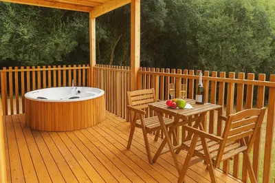 a deck with a tub and a table and chairs at Cabañas Compostela - Cabaña A Fervenza in Santiago de Compostela