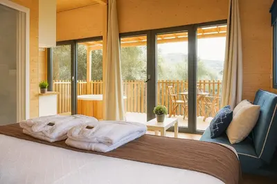 a bedroom with a large bed and a balcony at Cabañas Compostela - Cabaña A Fervenza in Santiago de Compostela