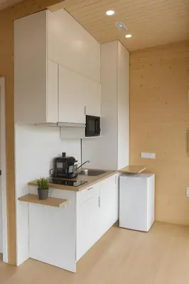 a kitchen with white cabinets and a refrigerator at Cabañas Compostela - Cabaña A Fervenza in Santiago de Compostela