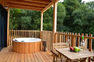 a wooden deck with a hot tub and a table with apples at Cabañas Compostela - Cabaña Pedroso con bañera de hidromasaje in Santiago de Compostela