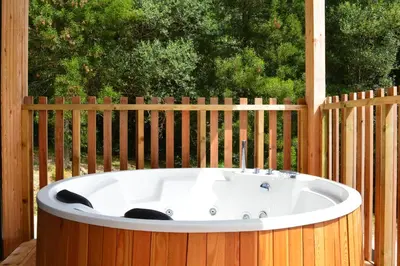 a bath tub sitting in front of a wooden fence at Cabañas Compostela - Cabaña Pedroso con bañera de hidromasaje in Santiago de Compostela