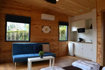 a living room with a blue couch and a kitchen at Cabañas Compostela - Cabaña Pedroso con bañera de hidromasaje in Santiago de Compostela