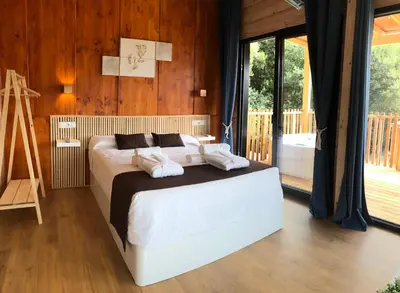 a bedroom with a bed and a large window at Cabañas Compostela - Cabaña Pedroso con bañera de hidromasaje in Santiago de Compostela