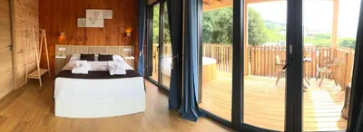 a bedroom with a bed and a balcony with sliding glass doors at Cabañas Compostela - Cabaña Pedroso con bañera de hidromasaje in Santiago de Compostela