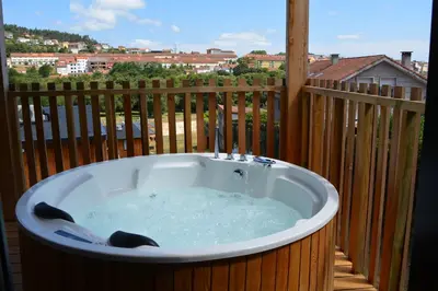 a hot tub on a balcony with a view of a city at Cabañas Compostela - Cabaña La Catedral con bañera de hidromasaje in Santiago de Compostela